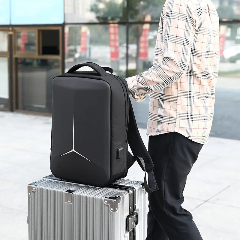 Man holding a hard-shell waterproof laptop backpack on a suitcase, designed for 15 to 17 inch laptops with anti-theft features and travel-ready design.